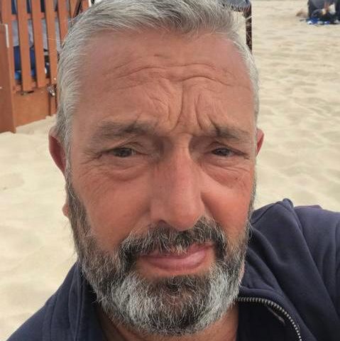 Andreas, engagierter Babyschwimmtrainer in Hamburg, lächelt freundlich in einem Porträtfoto am Strand