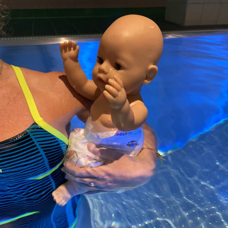 Demonstration mit Babypuppe im Wasser zur Schulung der sicheren Griffe beim Babyschwimmen Hamburg