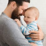 Glücklicher Vater hält sein lachendes Baby in den Armen – inniger Moment voller Geborgenheit
